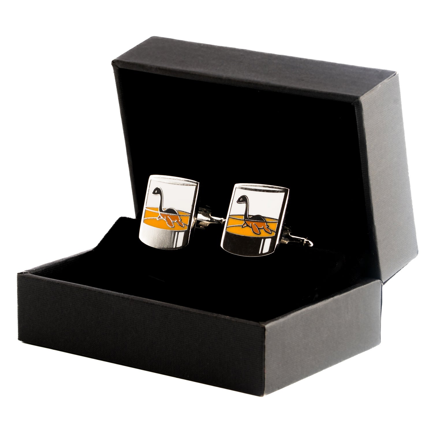 A pair of silver-colored cufflinks with an image of the Loch Ness Monster on them, presented in an open black box.
