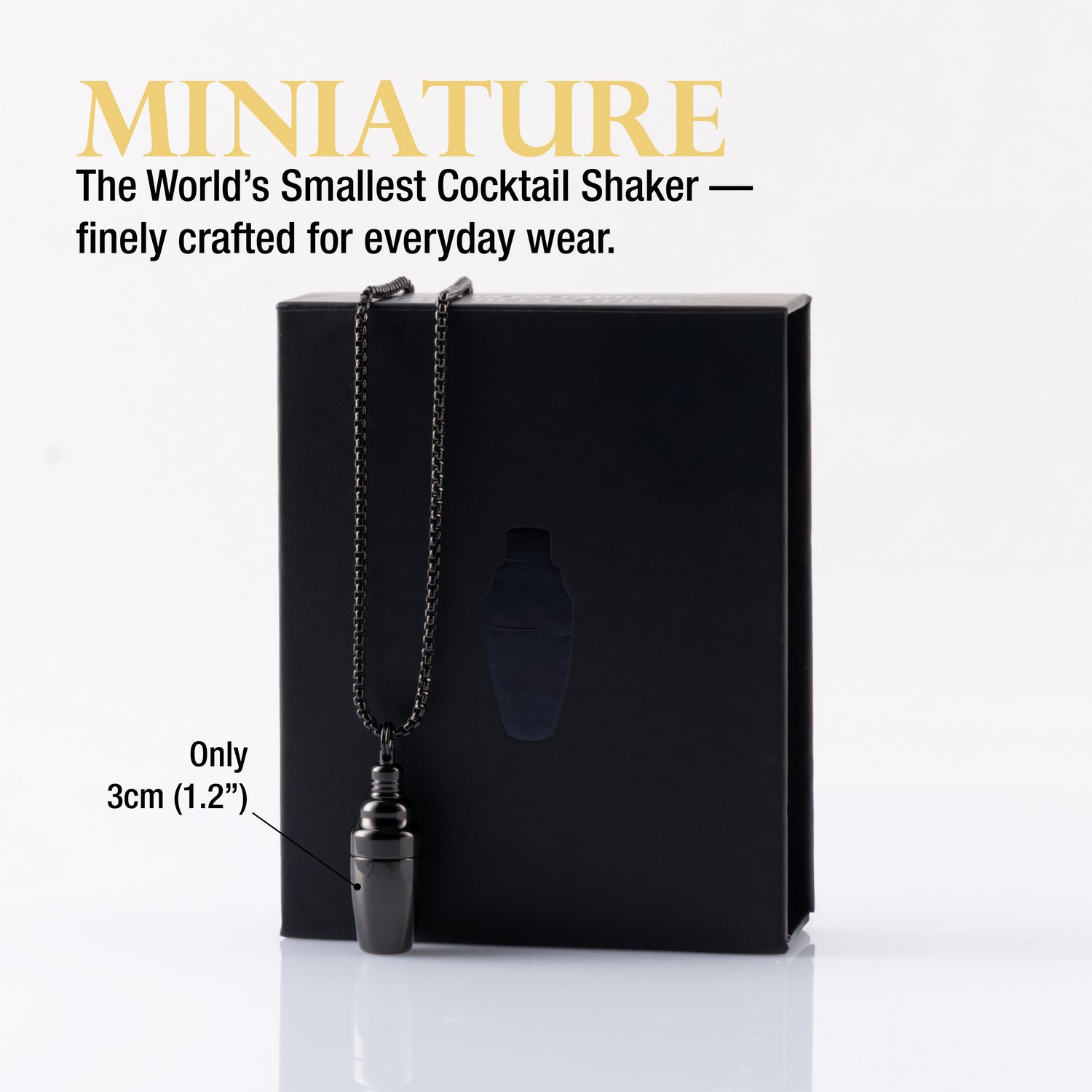 Miniature black cocktail shaker necklace in front of a black gift box.