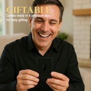 Man holding a small black gift box with a black logo, smiling, in a home setting.