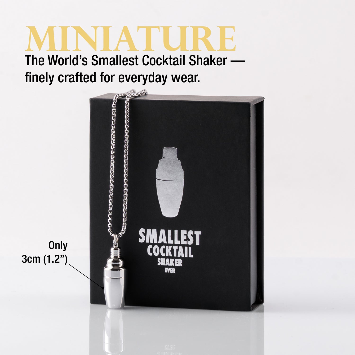 Miniature cocktail shaker necklace in front of a black gift box with the name "Smallest Cocktail Shaker Ever"